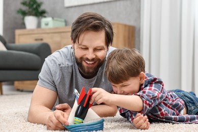 Photo of Happy dad and son playing toys together at home