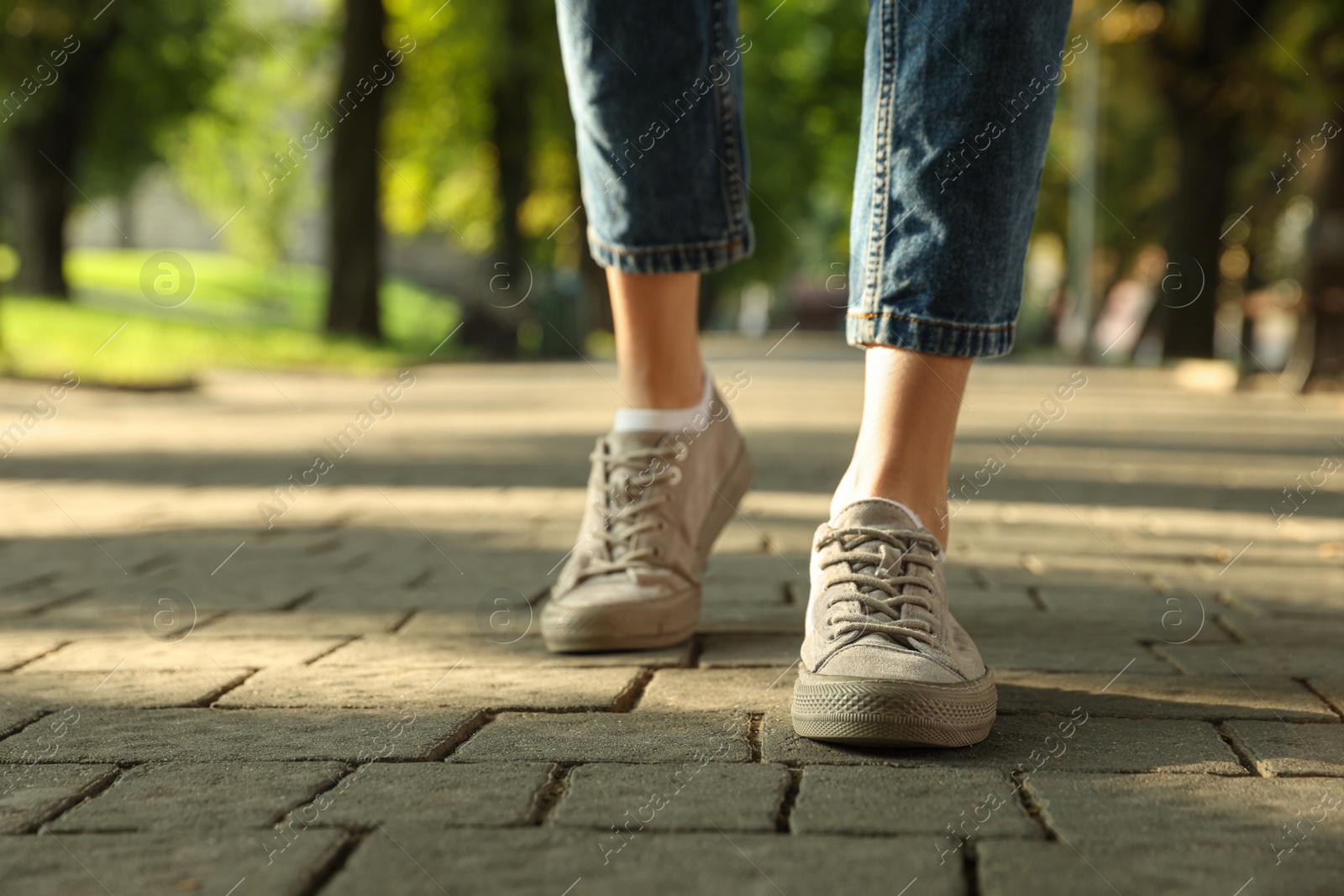 Photo of Woman in stylish sneakers walking on city street, closeup. Space for text