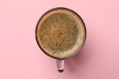 Aromatic coffee in glass cup on pink background, top view