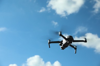 Modern drone with camera flying in sky on sunny day