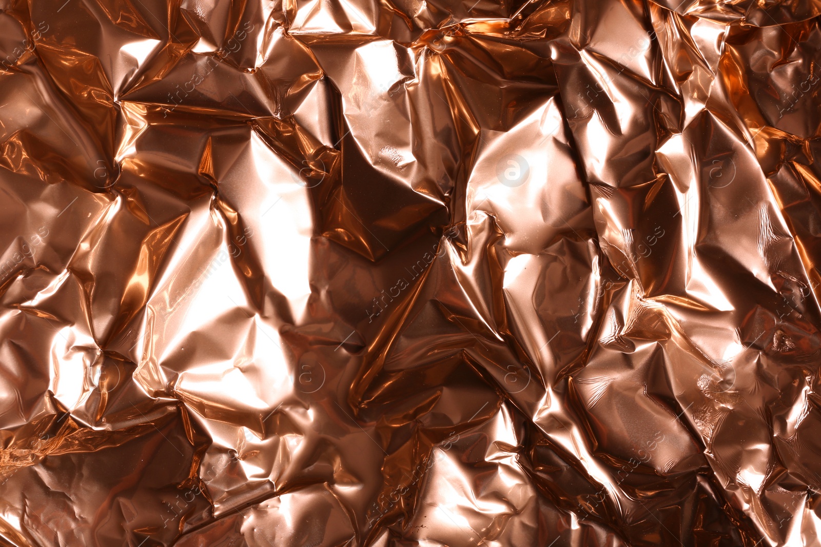 Photo of Crumpled rose gold foil as background, closeup view