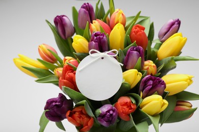 Bouquet of colorful tulips with blank card on white background, closeup