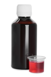 Bottle of cough syrup and measuring cup on white background