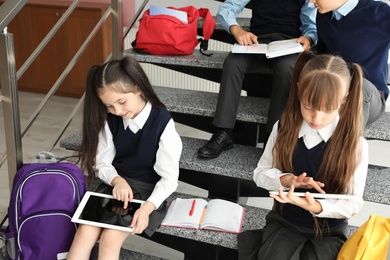 Photo of Little children in stylish school uniform on stairs indoors