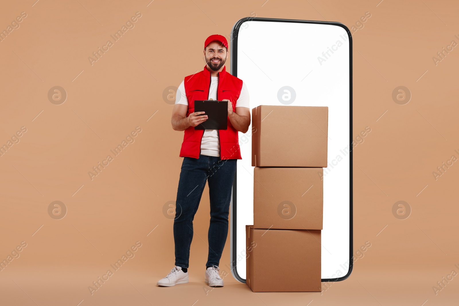 Image of Courier with stack of parcels and clipboard near huge smartphone on dark beige background. Delivery service