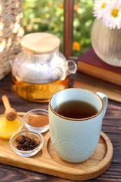 Photo of Tray with delicious tea and ingredients on wooden table