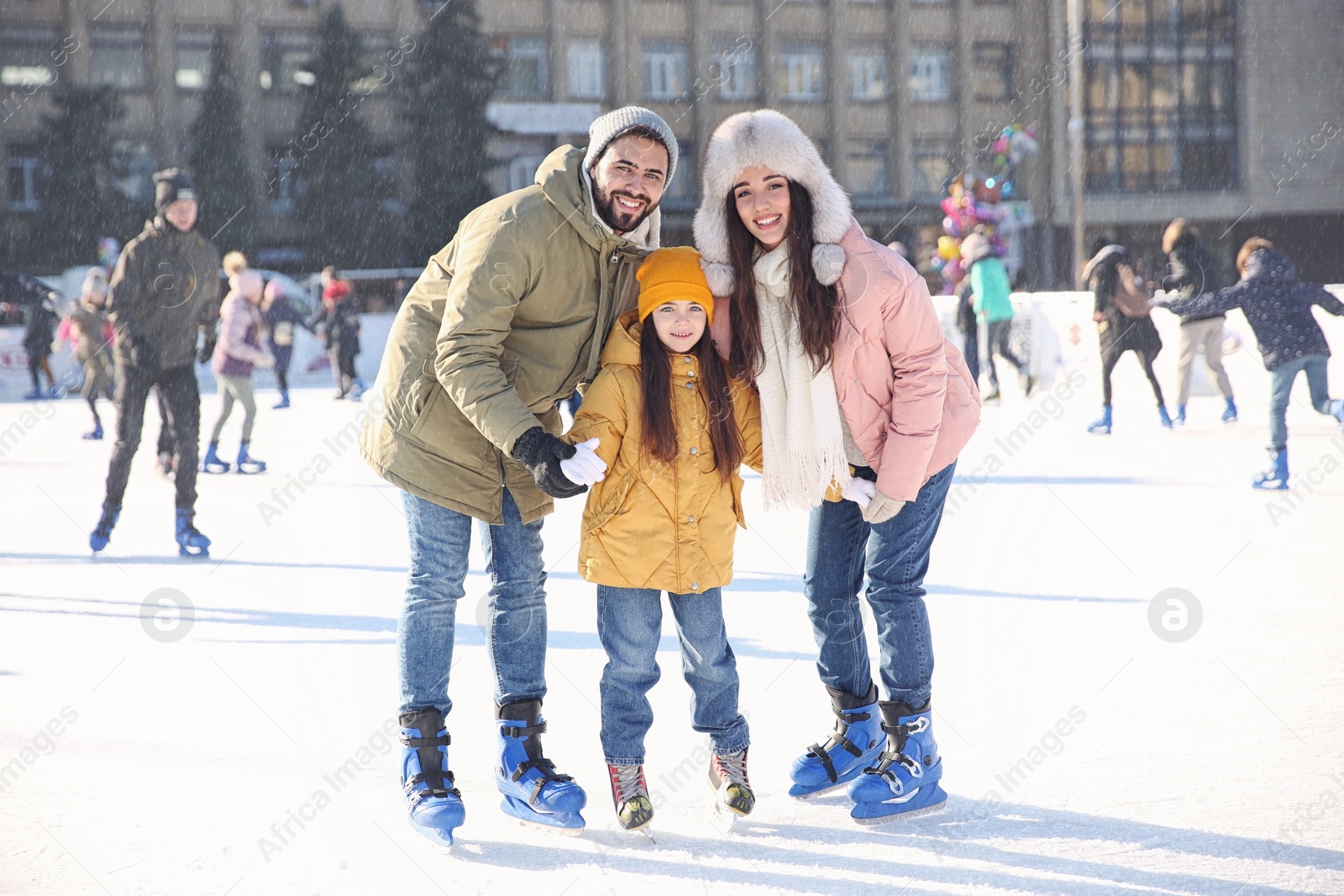 Image of Happy family spending time together at outdoor ice skating rink