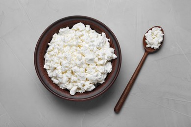 Clay bowl and spoon with cottage cheese on grey table, flat lay