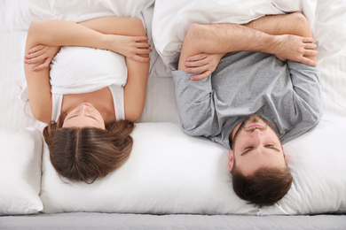 Photo of Upset young woman near sleeping husband in bed, top view. Relationship problems