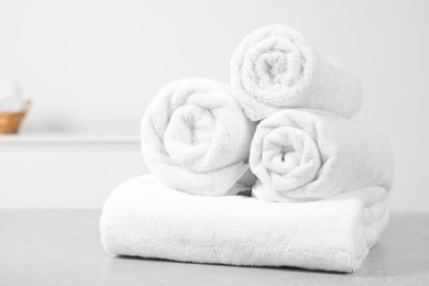 Photo of Clean soft rolled towels on white table