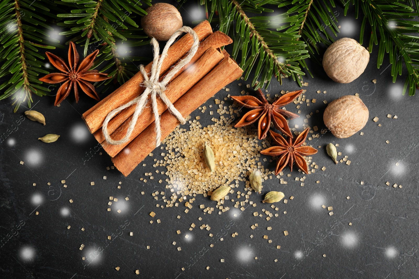 Image of Different spices and fir tree branches on dark table, flat lay. Cinnamon, anise, cardamom, nutmegs