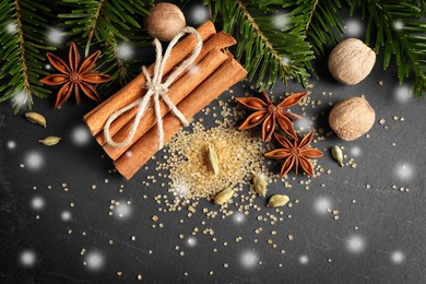 Different spices and fir tree branches on dark table, flat lay. Cinnamon, anise, cardamom, nutmegs