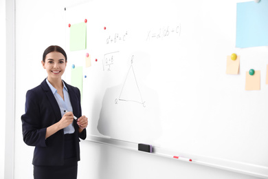 Photo of Young teacher near whiteboard in modern classroom