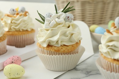 Photo of Tasty Easter cupcakes with vanilla cream on white marble table