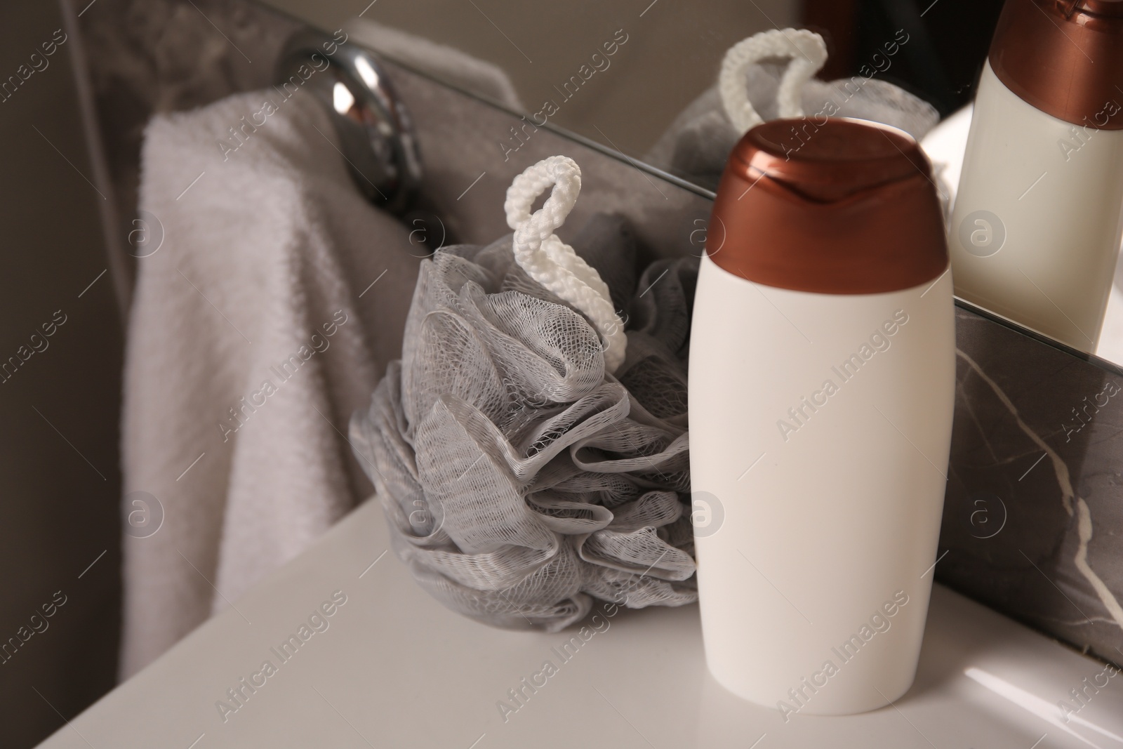 Photo of Grey sponge and shower gel bottle on washbasin in bathroom, closeup