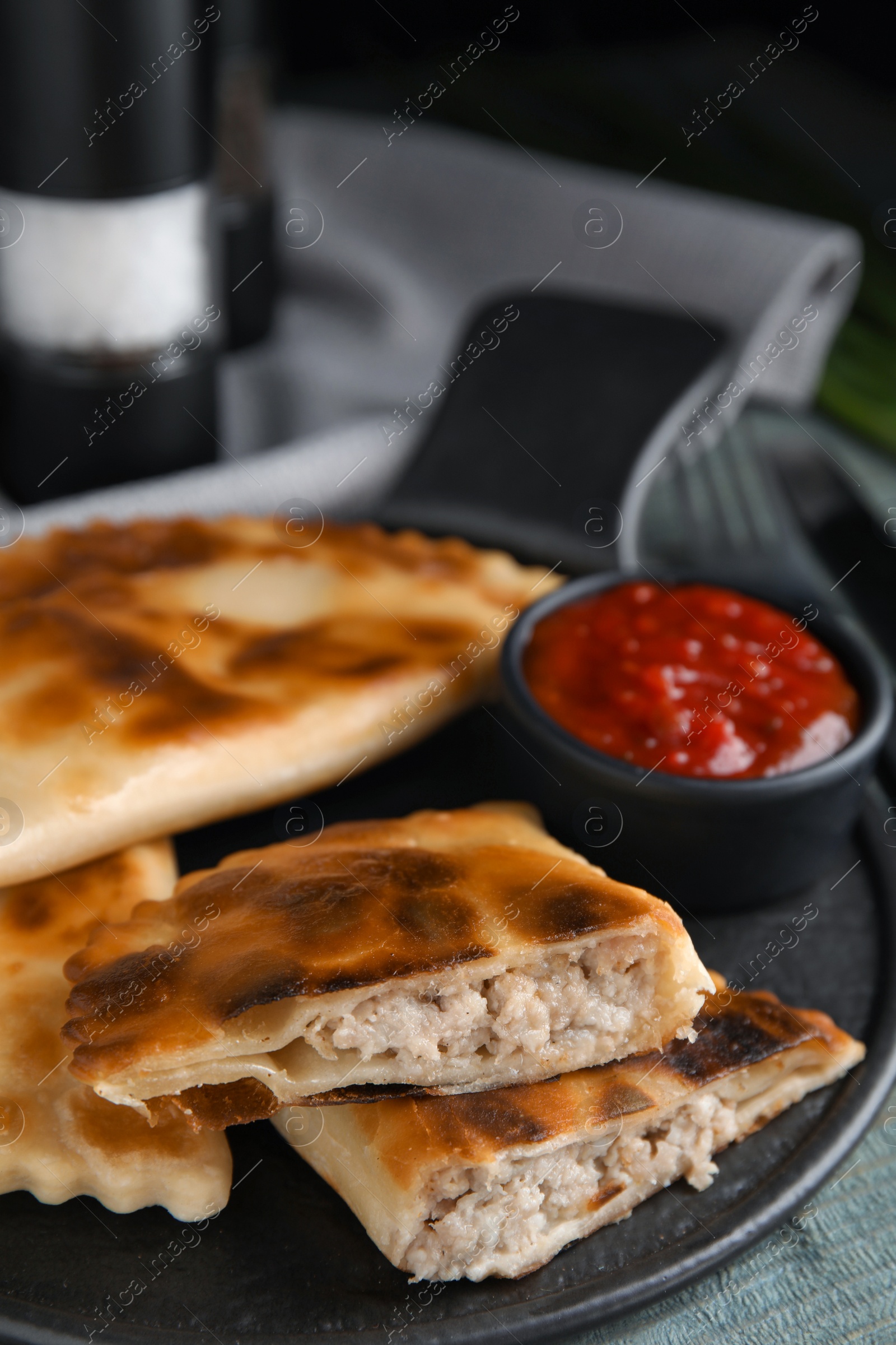 Photo of Delicious fried chebureki with ketchup on blue wooden table