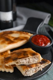 Photo of Delicious fried chebureki with ketchup on blue wooden table