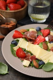 Photo of Tasty salad with brie cheese, prosciutto, almonds and berries on table, closeup