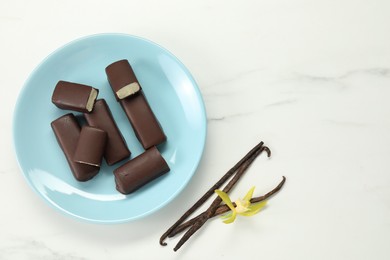 Photo of Glazed curd cheese bars, vanilla pods and flower on white marble table, flat lay. Space for text