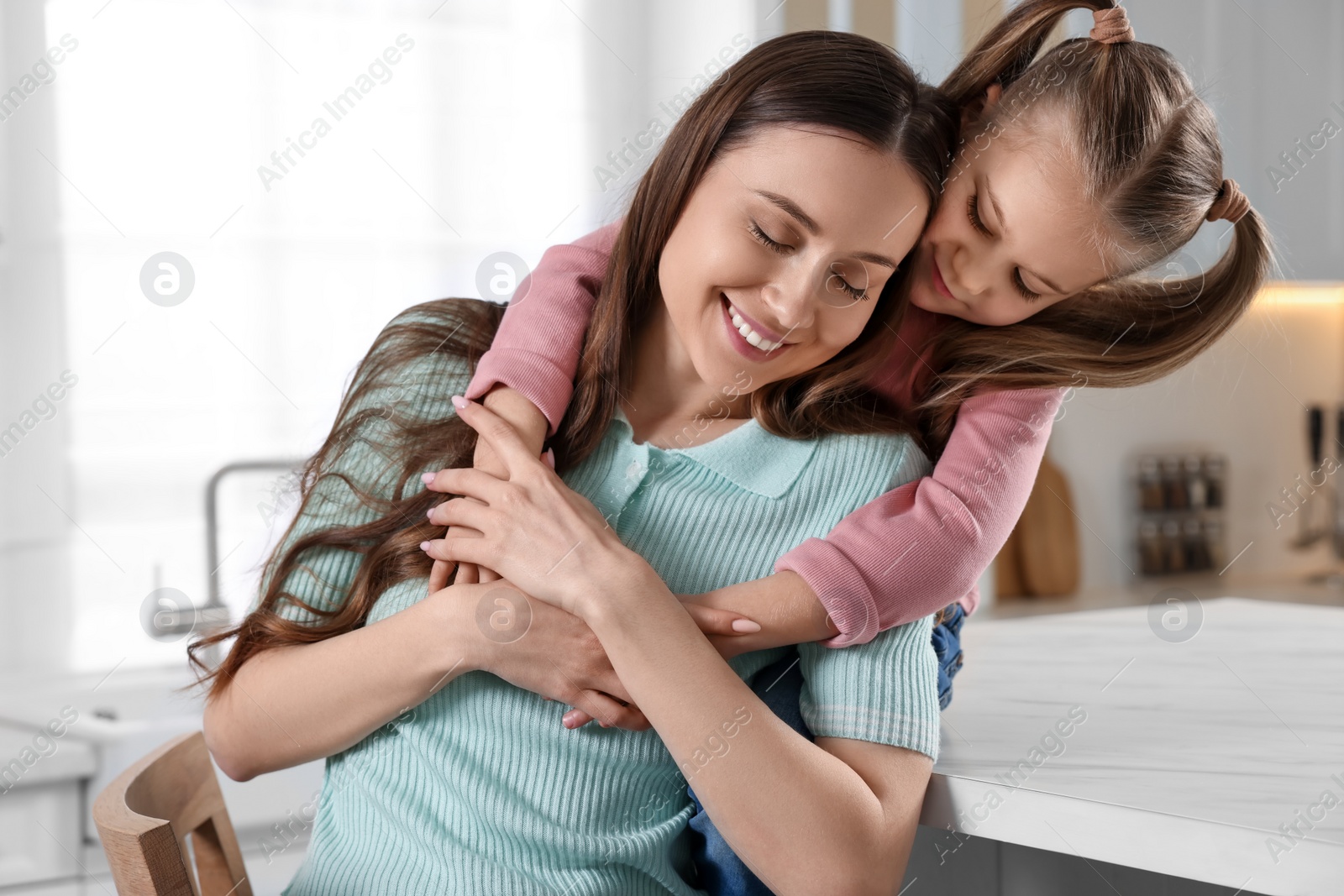 Photo of Happy mother with her cute daughter in kitchen