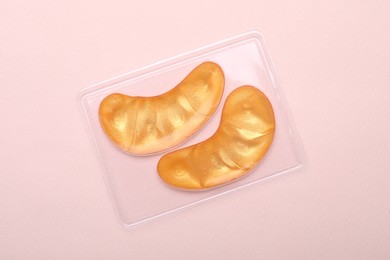Photo of Package with under eye patches on light pink background, top view. Cosmetic product