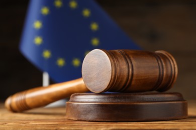 Judge's gavel and European Union flag on wooden table, closeup