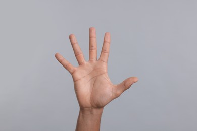 Man giving high five on grey background, closeup of hand