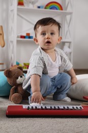 Photo of Cute little boy with toy piano at home