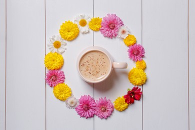 Photo of Beautiful floral composition with cup of hot coffee on white wooden background, flat lay