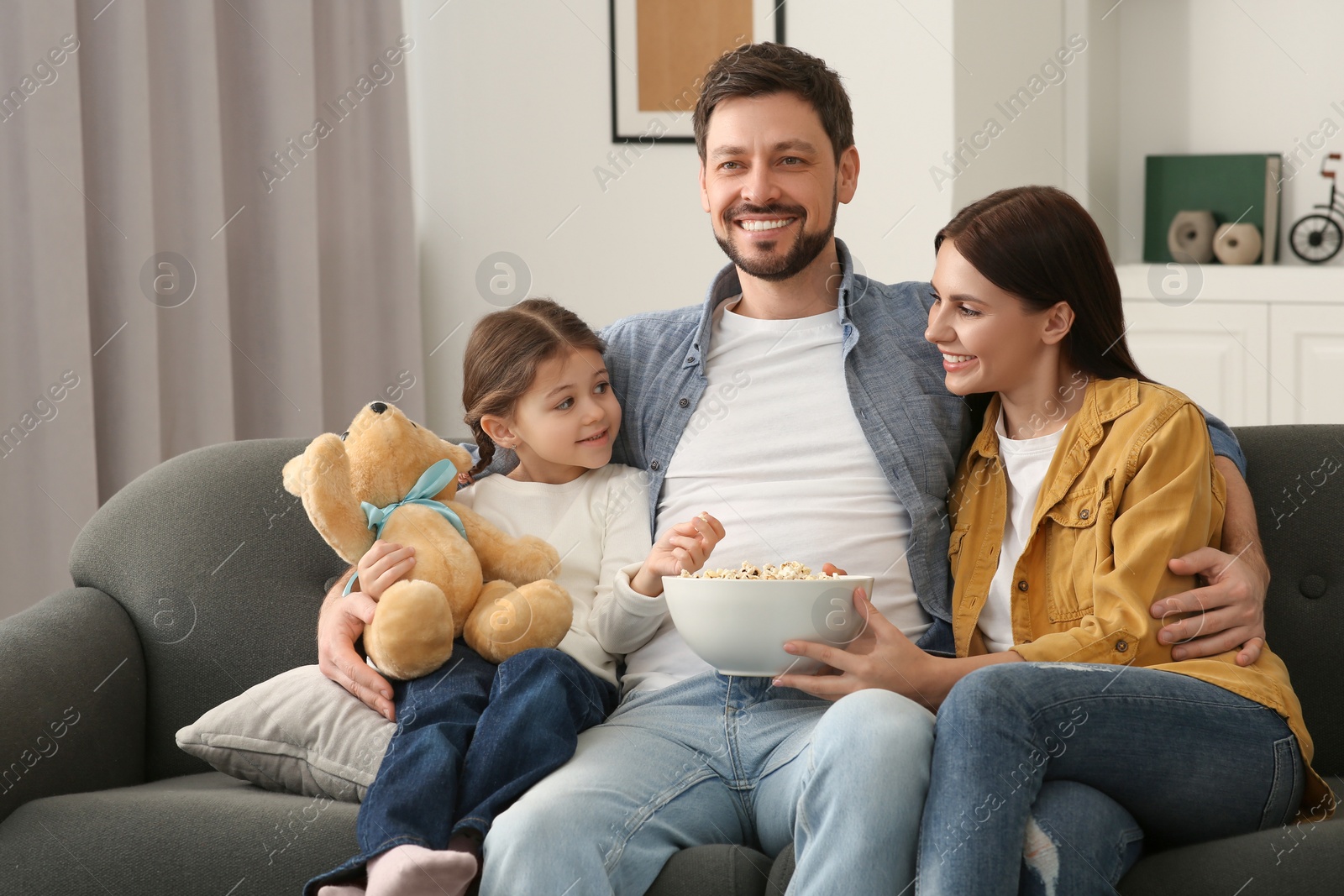 Photo of Happy family spending time together while watching TV at home