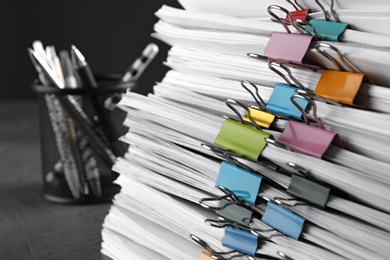 Photo of Stack of documents with binder clips on grey stone table, closeup view