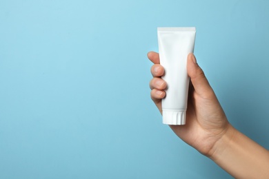 Photo of Woman holding blank toothpaste tube on color background. Space for text