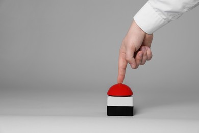 Photo of Man pressing red button of nuclear weapon on light gray background, closeup with space for text. War concept
