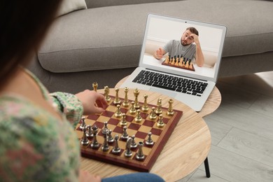 Image of Woman playing chess with partner via online video chat in living room, closeup