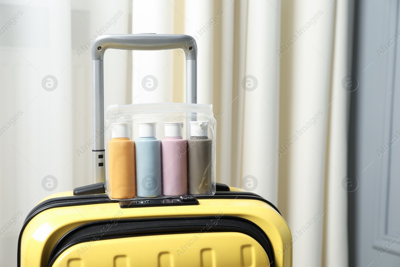 Photo of Cosmetic travel kit. Plastic bag with small containers of personal care products on suitcase indoors, space for text