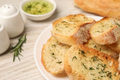 Tasty baguette with garlic and dill on white table, closeup