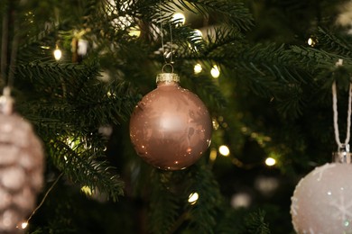 Photo of Beautiful baubles and fairy lights on Christmas tree, closeup