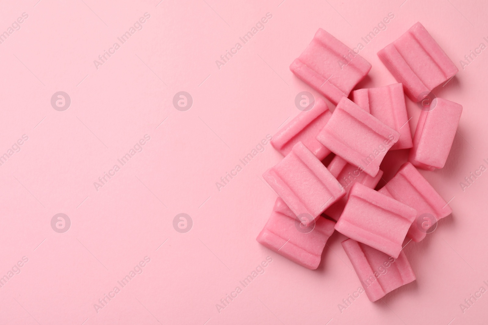 Photo of Tasty chewing gums on pink background, flat lay. Space for text