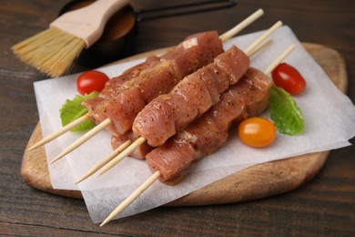 Photo of Skewers with cut raw marinated meat on wooden table