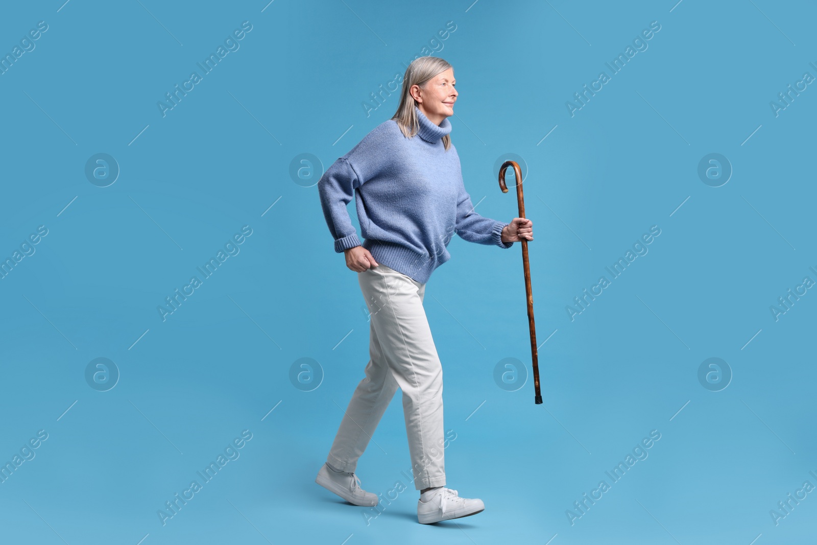 Photo of Senior woman with walking cane on light blue background