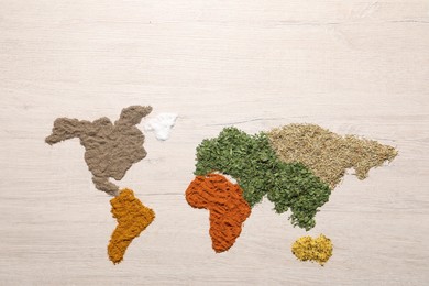 World map of different spices on wooden table, flat lay