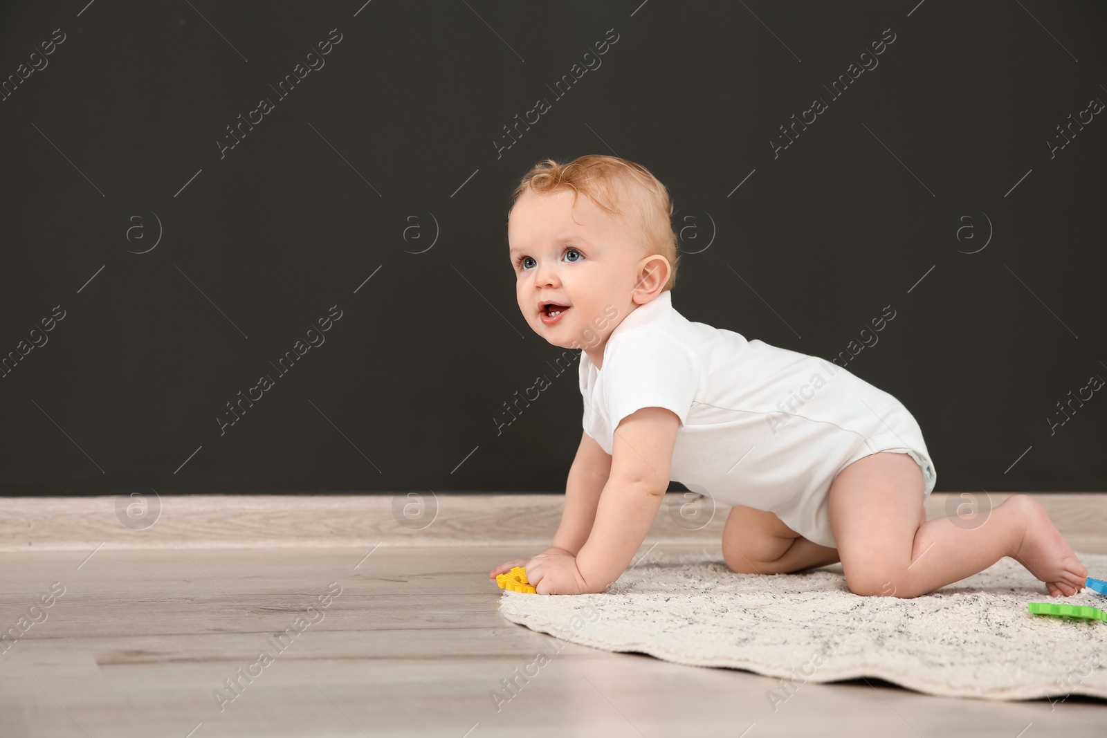 Photo of Cute little baby crawling on rug indoors, space for text