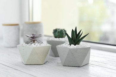 Photo of Beautiful succulent plants in stylish flowerpots on windowsill. Home decor