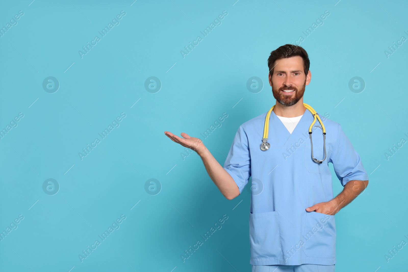 Photo of Happy doctor with stethoscope on light blue background. Space for text