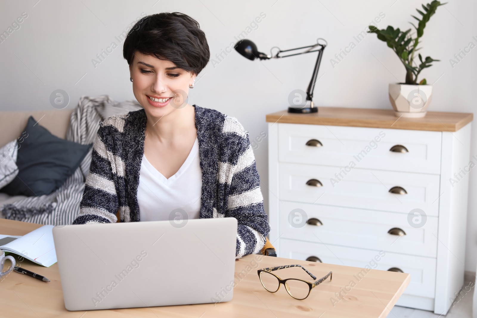 Photo of Young woman working with laptop at desk. Home office