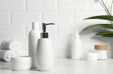 Photo of Different bath accessories and personal care products on white table near brick wall