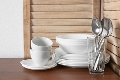 Photo of Set of clean dishes and cutlery on table in kitchen