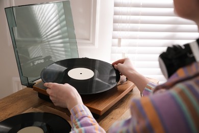 Young woman using turntable at home, closeup