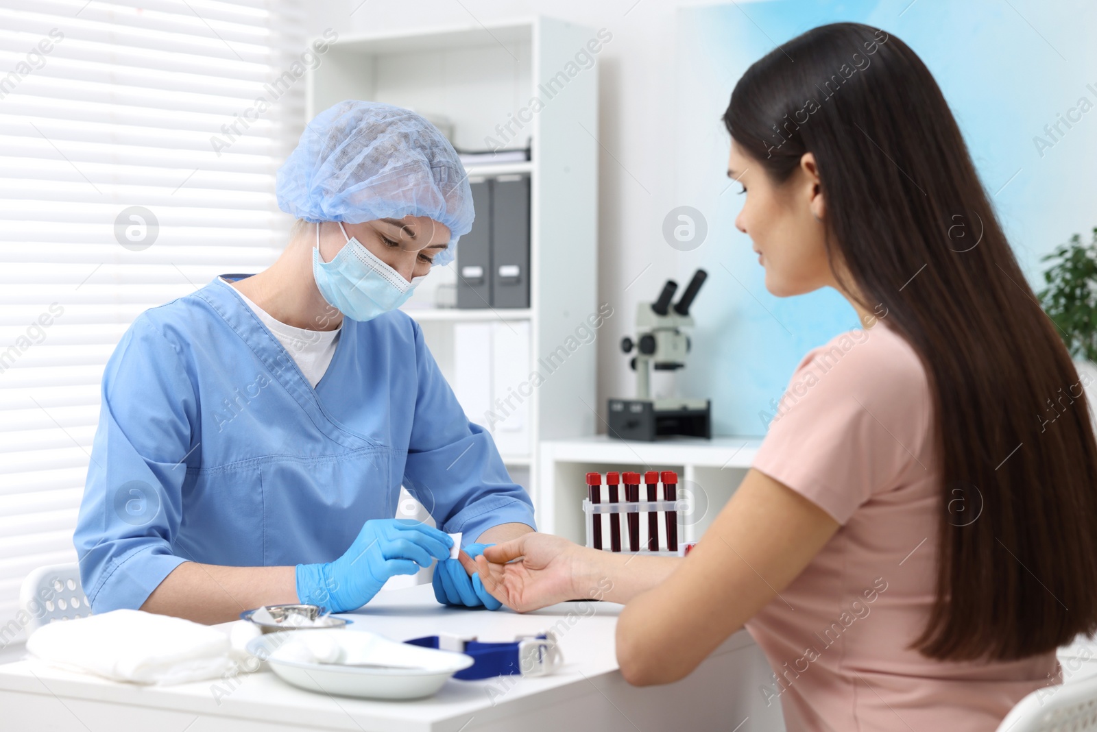 Photo of Laboratory testing. Doctor taking blood sample from patient at white table in hospital