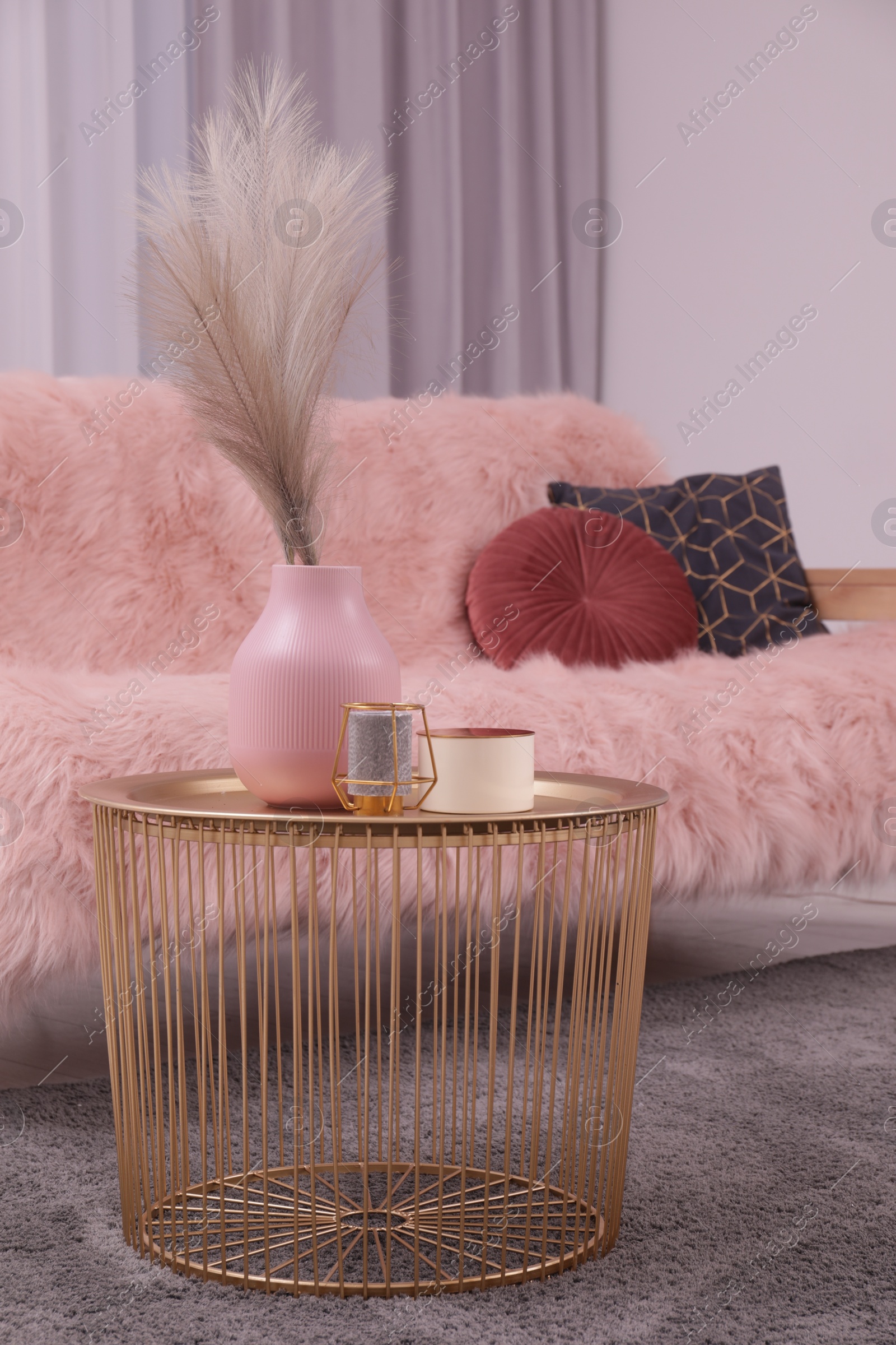 Photo of Vase and candles on coffee table near sofa in stylish room. Interior design